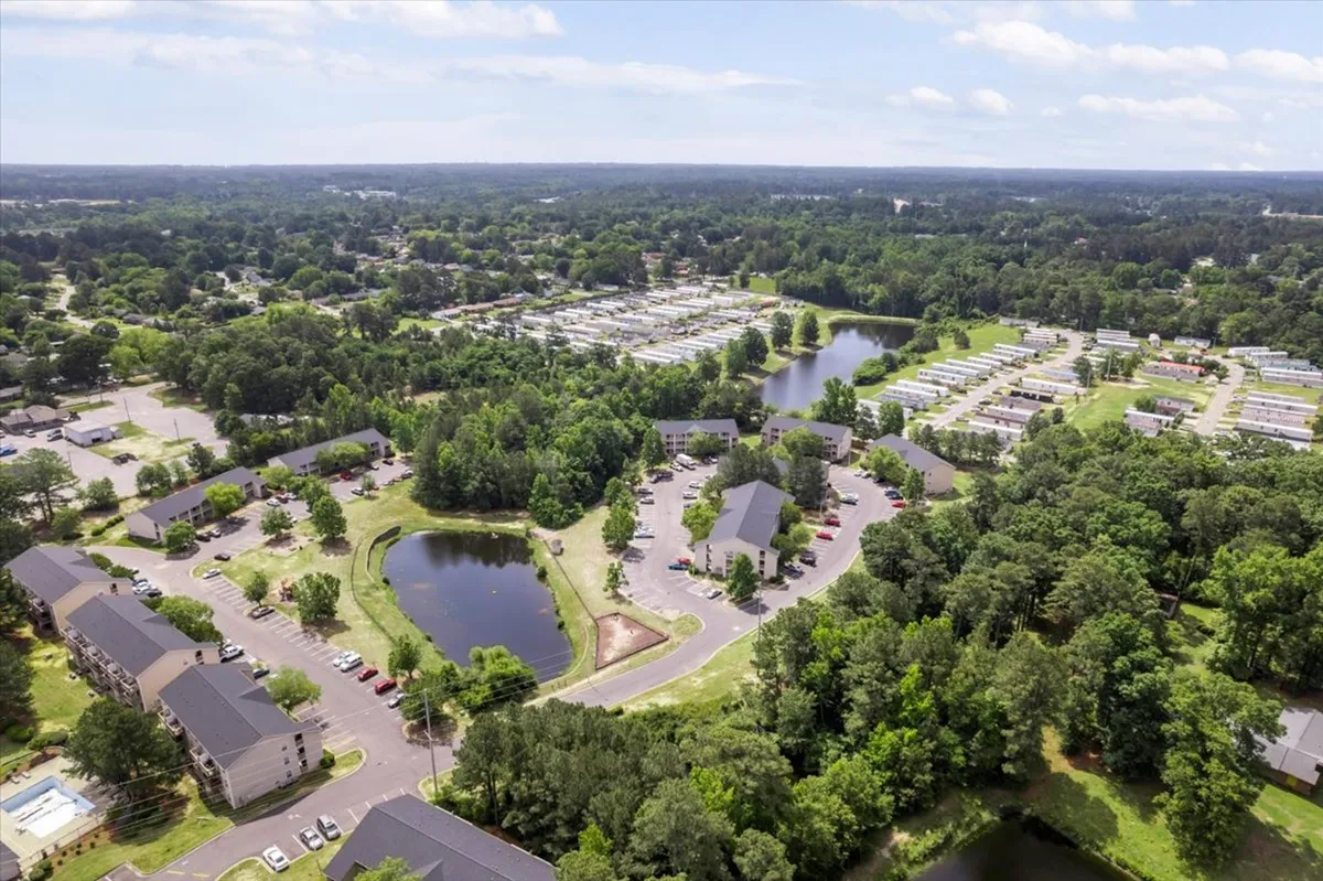 A wide view of lakes nestled among lush greenery with residential buildings and roads weaving through the landscape. The image conveys a sense of peacefulness and accessibility to nature, demonstrating a harmonious blend of community living and outdoor exploration.