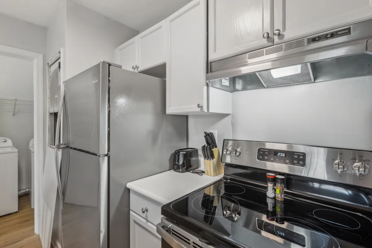 A sleek kitchen featuring stainless steel appliances, a black stove, and crisp white cabinetry. The layout is open and inviting, encouraging meal prep and socialization. This scene suggests a space where families can gather and prepare meals together, emphasizing the comfort of home-cooked experiences.